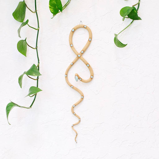 Tan speckled ceramic wall snake with pale blue dots, looped and hanging on a white textured wall