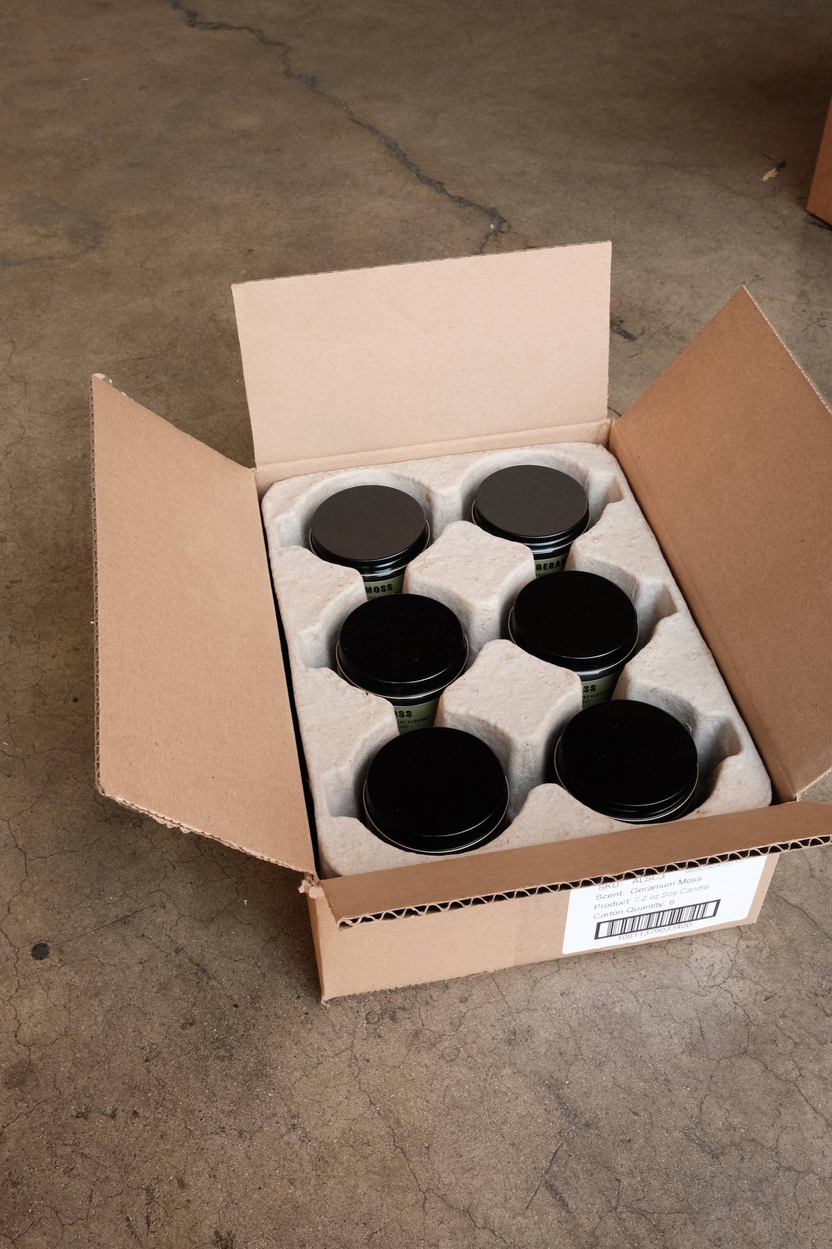 Six black-lidded jar candles packed in a pulp tray inside an open shipping box