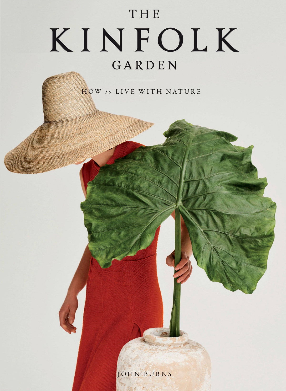 Full-bleed cover of The Kinfolk Garden, woman in red dress behind a giant leaf in a stone urn