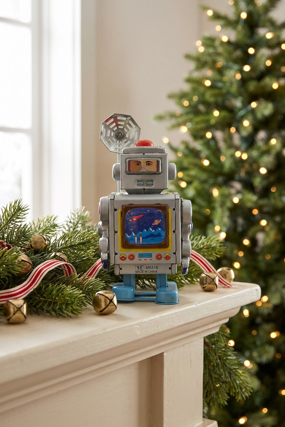Silver wind-up tin robot on a holiday mantel with evergreen garland