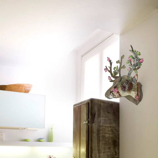Eco deer head mounted on a white wall above a rustic wooden cabinet in a bright room