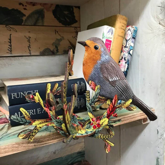 Little Jaky robin wall decor mounted on a rustic bookshelf in front of stacked vintage books