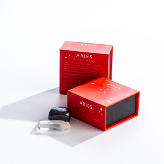 Aries mini stone pack text on two red boxes with Aries constellation pattern. Clear quartz and polished hematite stone in front.