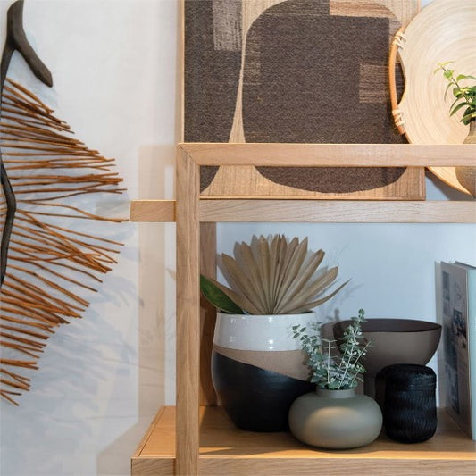 Assorted pots on light modern shelving unit with abstract natural art and objects