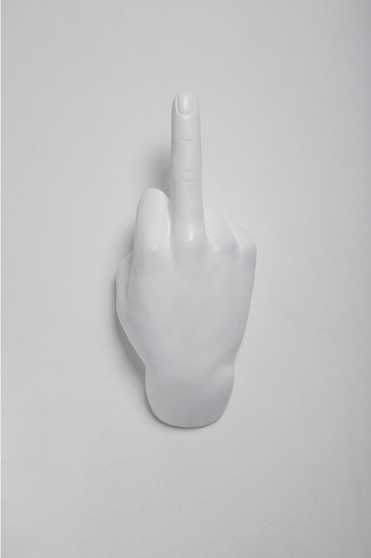 Full view of the white middle finger hand wall hook showing the wrist base against a gray wall