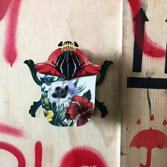 Ronnie beetle wall cabinet hung on plywood marked with red graffiti, floral wings closed