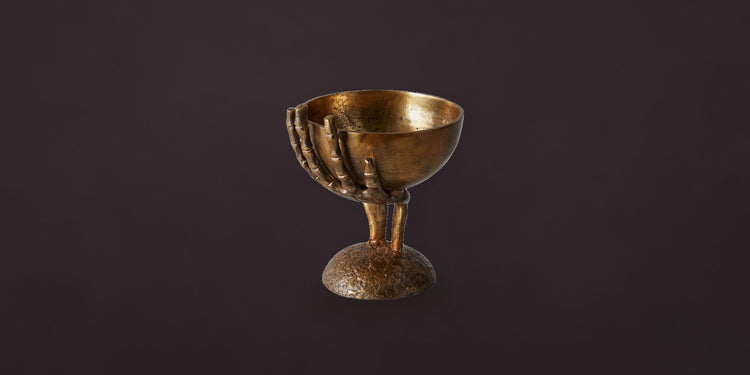 Brass skeleton hand bowl on a dark plum backdrop - Onederkam Halloween decor
