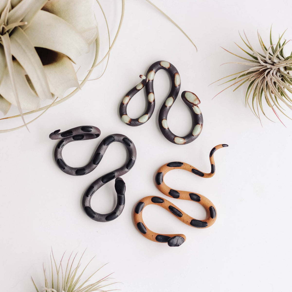 Ceramic snake set in darker colors: brown with cream spots, gray with black spots, tan with black bands