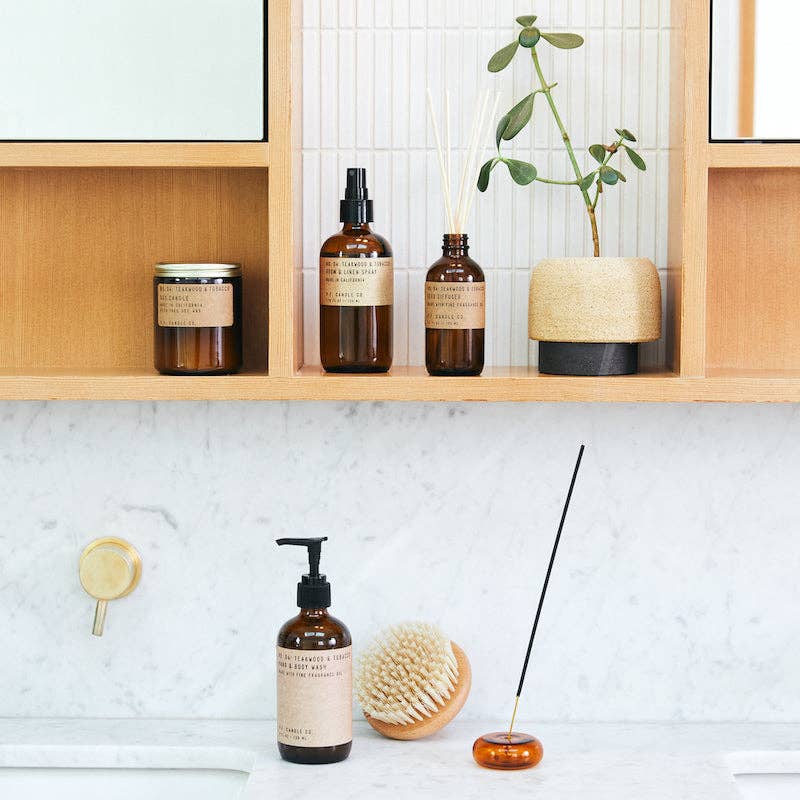 Teakwood & Tobacco incense in an amber holder on a marble vanity with matching soap, candle and diffuser