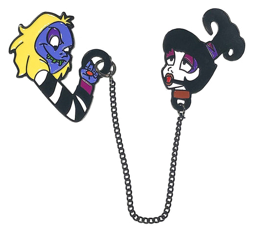 Close-up of the Mischievous Love enamel pins showing purple, yellow, and black-and-white details