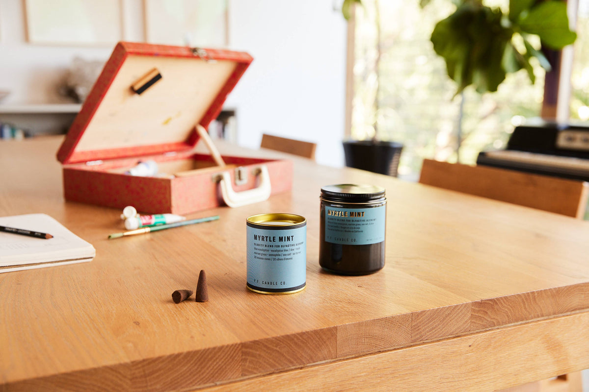 Myrtle Mint jar candle and matching tin with incense cones on a wooden table