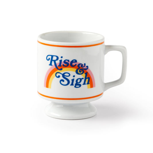 White pedestal mug with orange stripes and blue Rise & Sigh script over a pastel rainbow