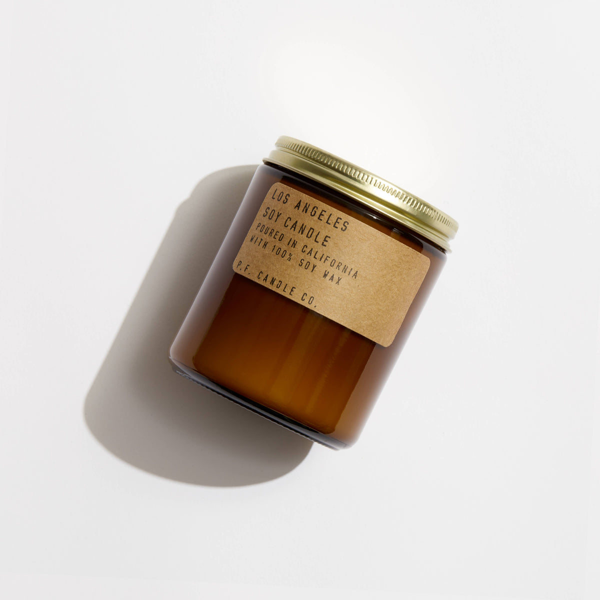 Los Angeles soy candle in an amber jar with a brass lid and kraft label, shown from above