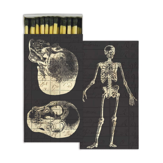 Infirmerie matchbox in black with vintage skull drawings on one side, a full skeleton on the other, black-tipped matches