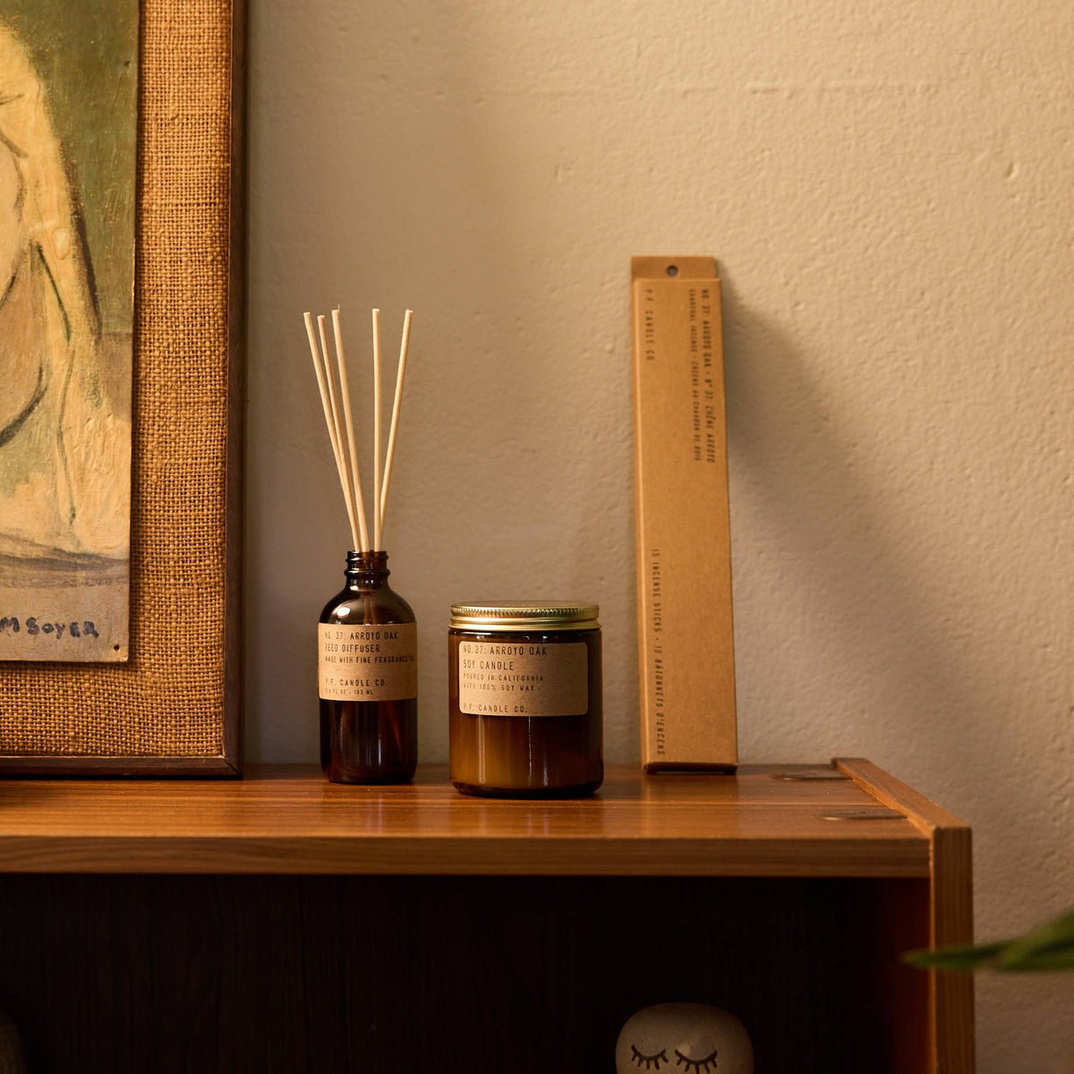 Arroyo Oak candle styled on a wooden shelf beside a matching reed diffuser and an incense box