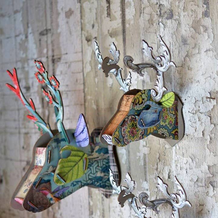 Two eco deer heads with different patterns mounted on a weathered white wood wall