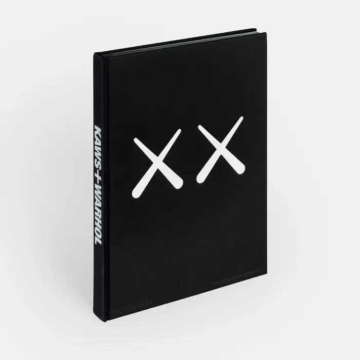 Kaws + Warhol book standing upright, black cover with two white KAWS X marks and title on the spine