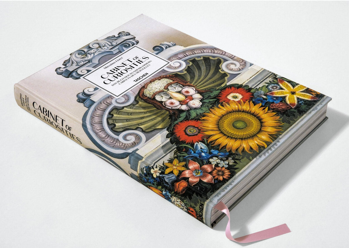Cabinet of Curiosities book lying flat at an angle, showing the spine and a pink ribbon bookmark