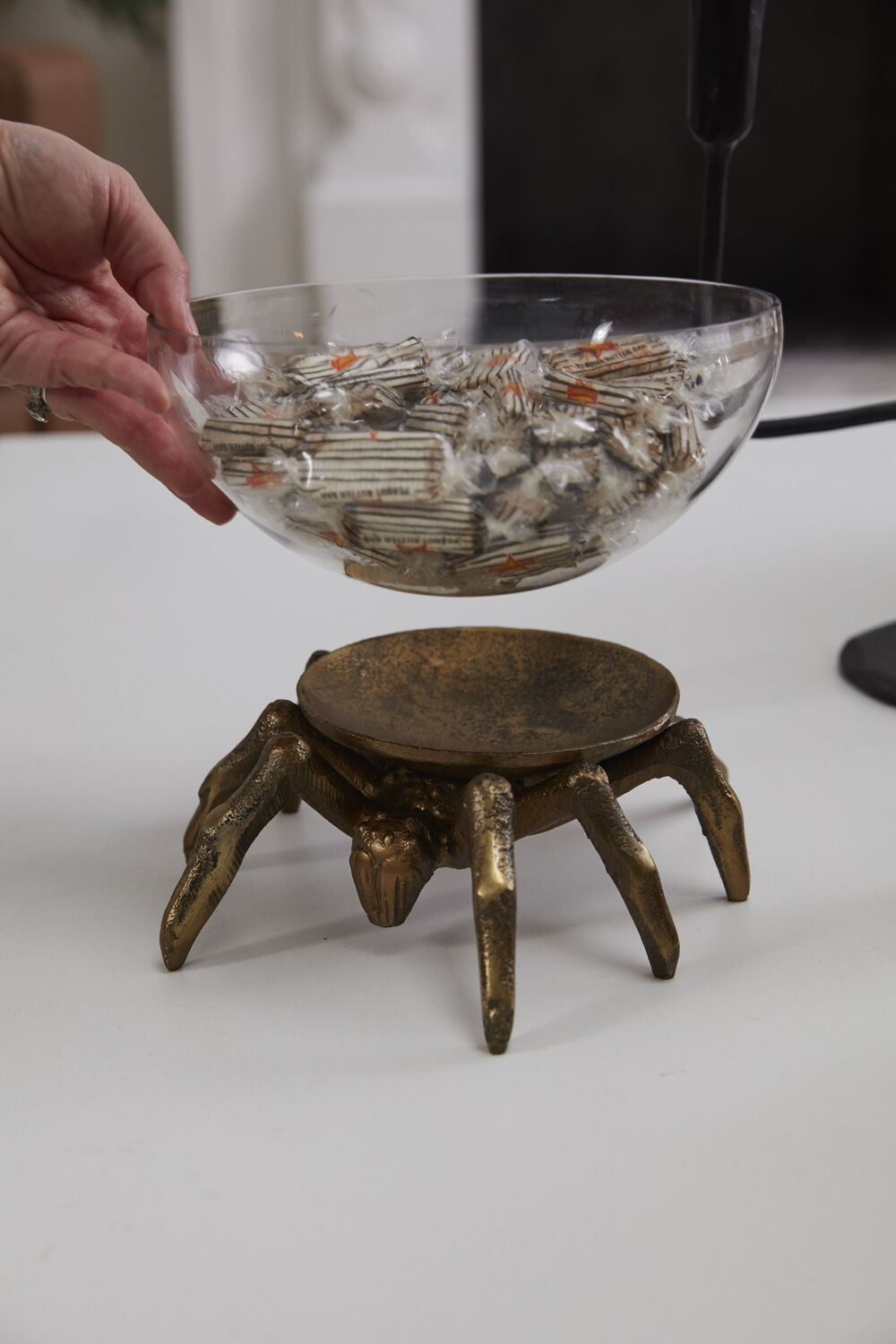 Glass bowl filled with candy lifting off the gold spider stand