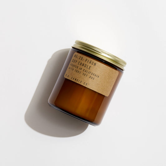 Piñon soy candle in an amber glass jar with gold lid and kraft label reading No. 20 Piñon, shown from above