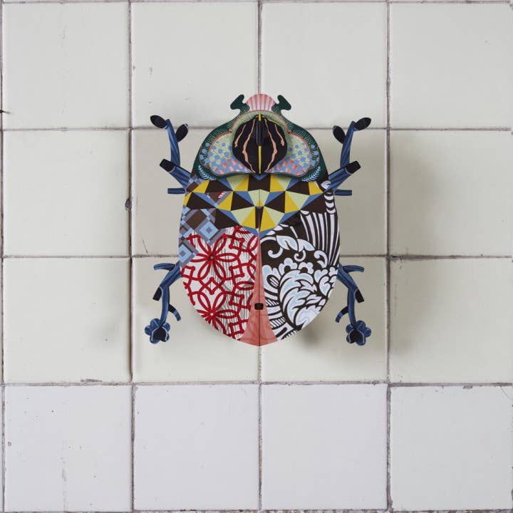 John Beetle wall cabinet hung on a cream tiled wall, wings closed, with blue-gray legs