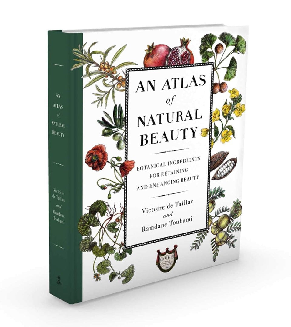 An Atlas of Natural Beauty hardcover standing at an angle, showing the dark green spine and illustrated cover