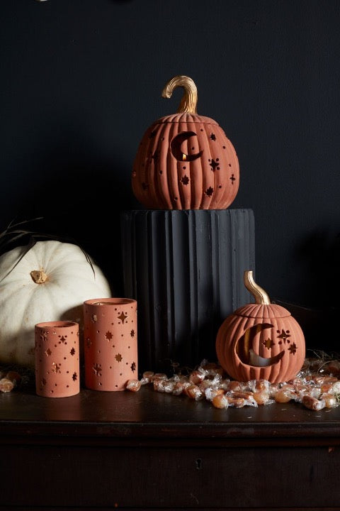 Ceramic votive and pumpkins with cutout moon and stars.