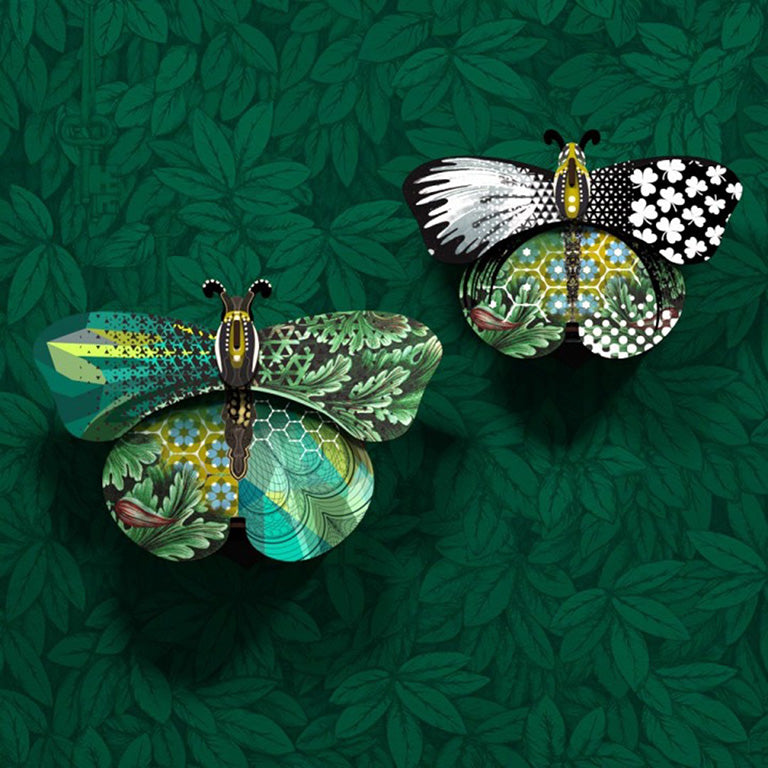 Two butterfly wall cabinets on green leaf wallpaper, one with green leaf-patterned wings, one black and white