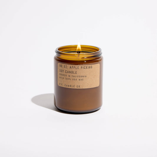 Apple Picking soy candle lit, lid off, amber glass jar with kraft label on white