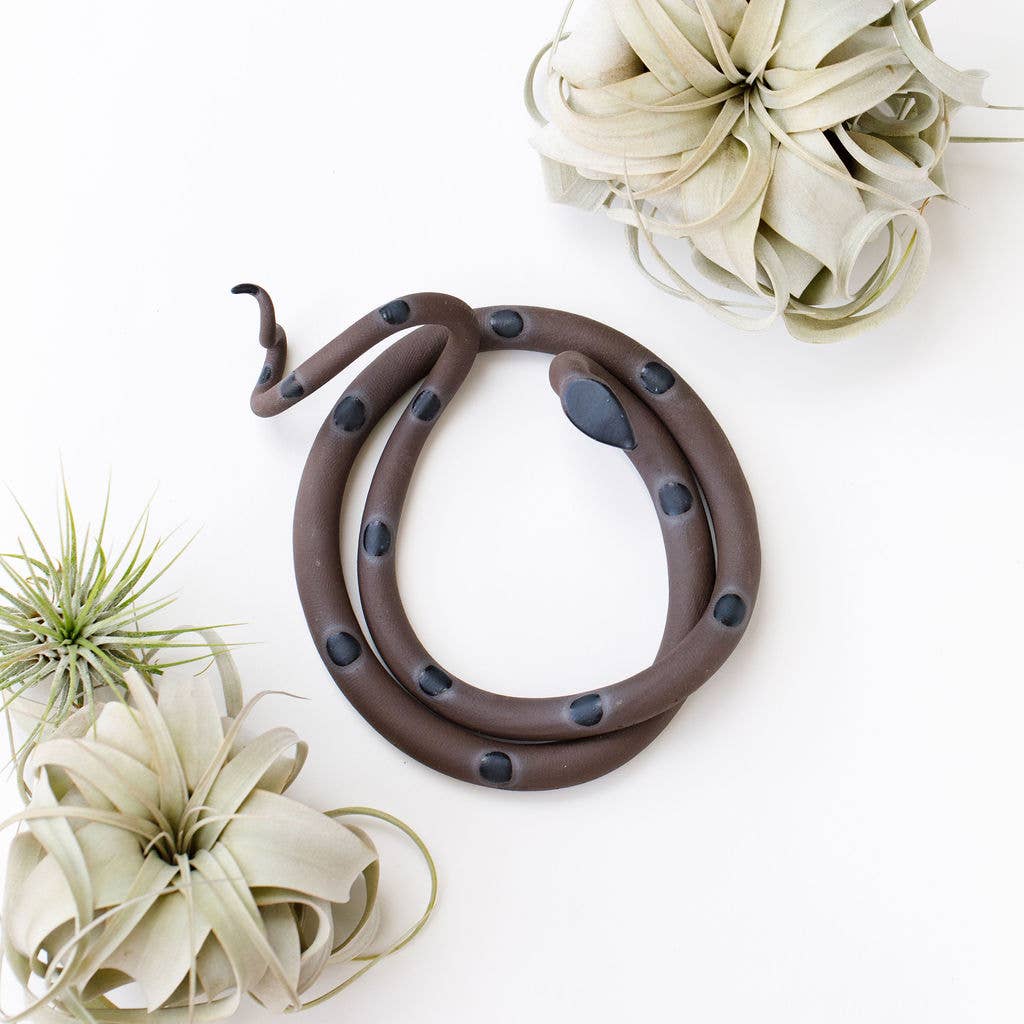 Coiled brown ceramic snake with dark gray spots, shown from above among air plants