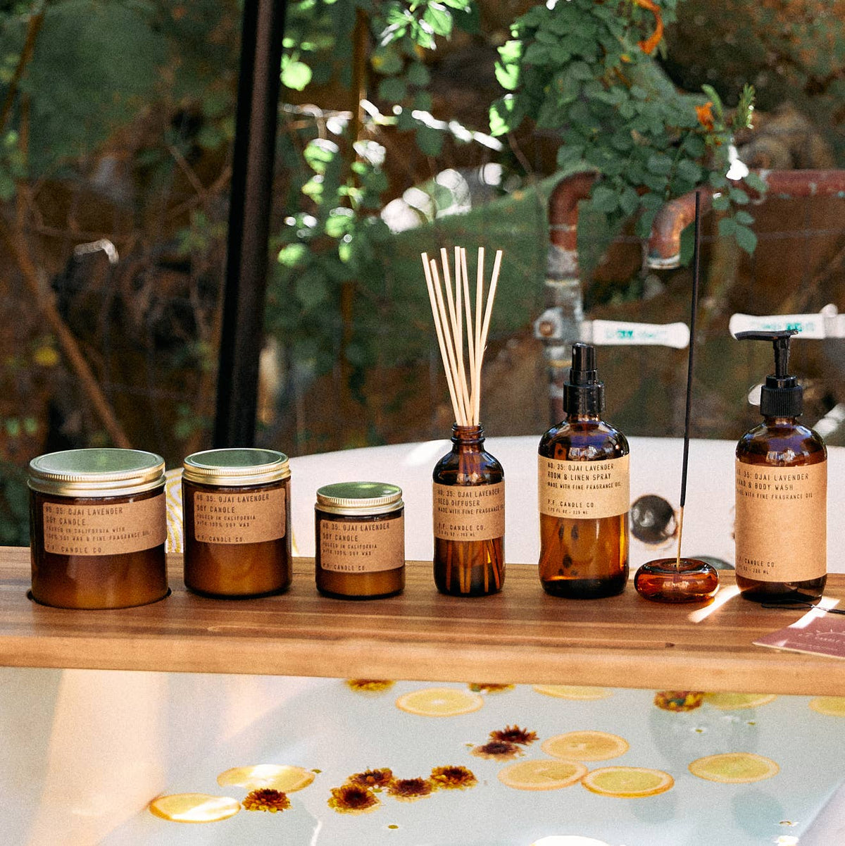 Ojai Lavender candles, reed diffuser, sprays, and lit incense on a bathtub tray