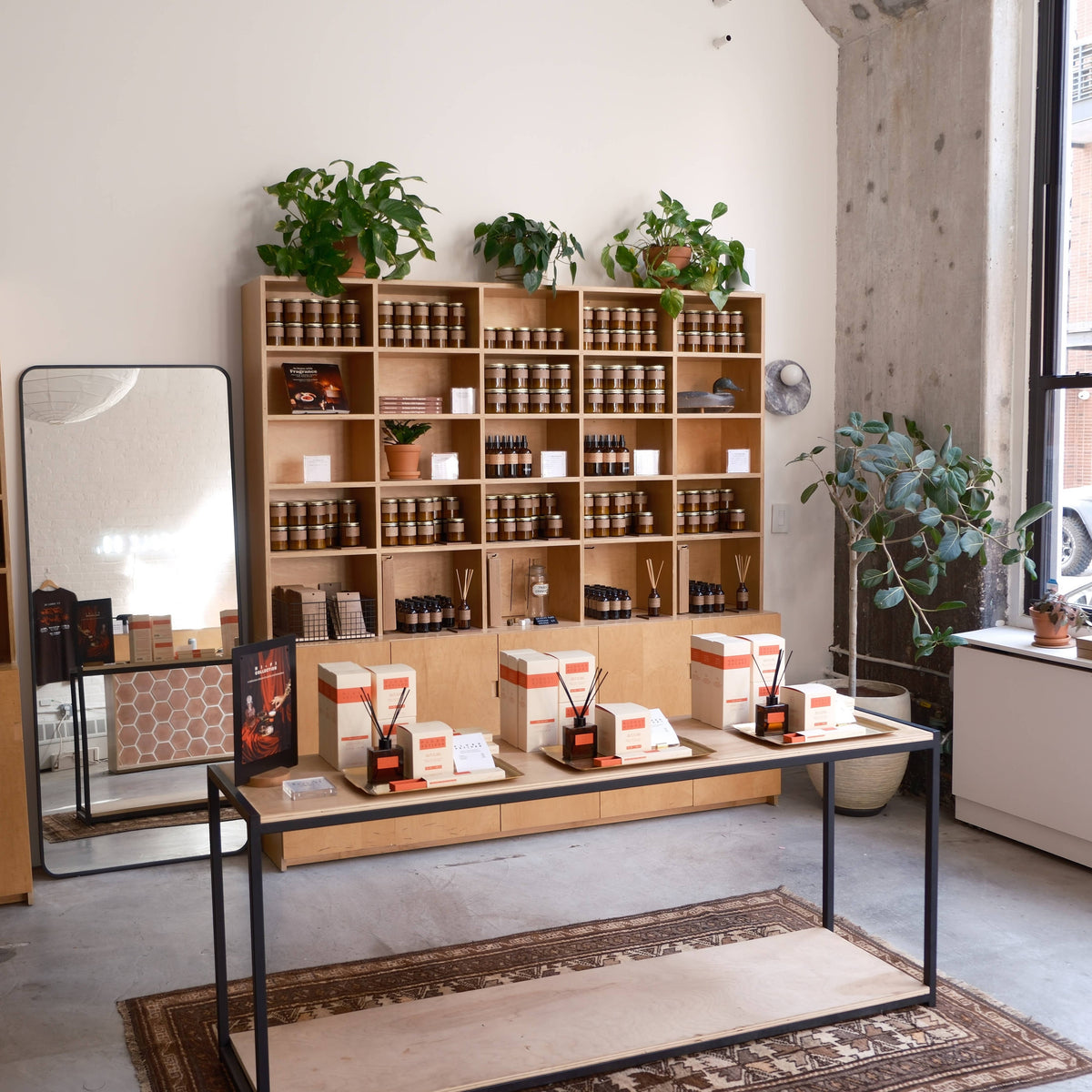 Candle shop interior with shelves of amber jar candles and a center table of diffusers