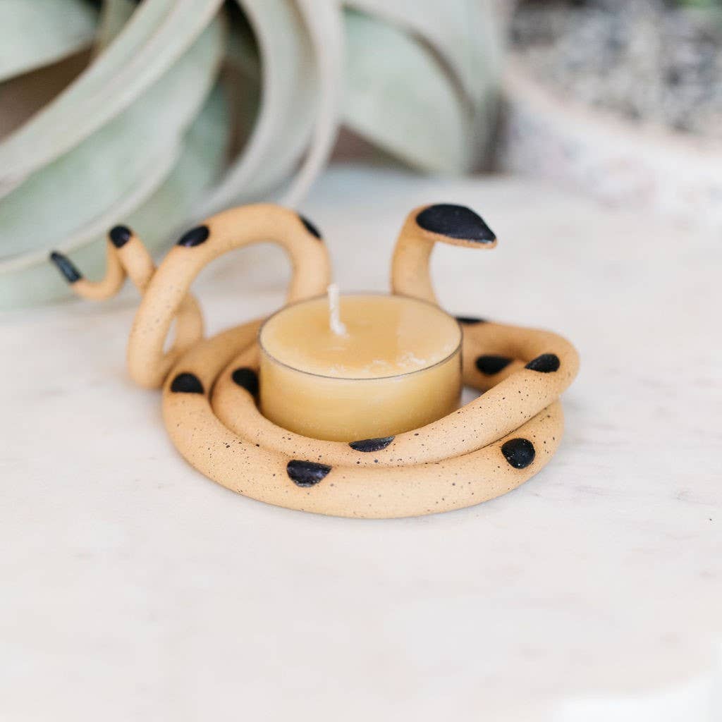 Speckled tan ceramic snake tealight holder with black spots and a black head around a beeswax tealight