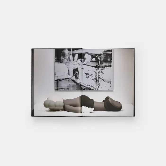 Kaws + Warhol spread showing a reclining gray KAWS figure below a black and white Warhol ambulance image