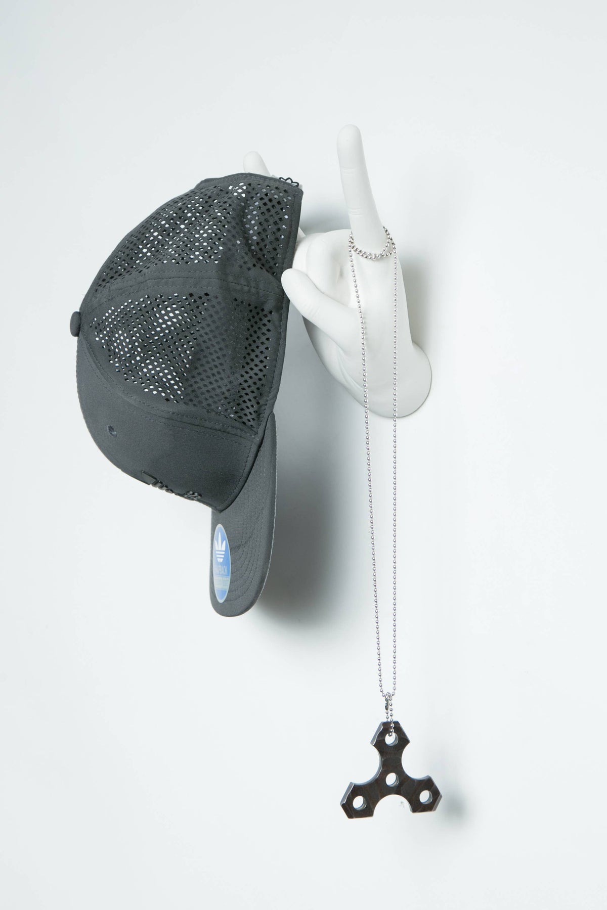 Rock On hand hook holding a black baseball cap and a ring with a pendant necklace