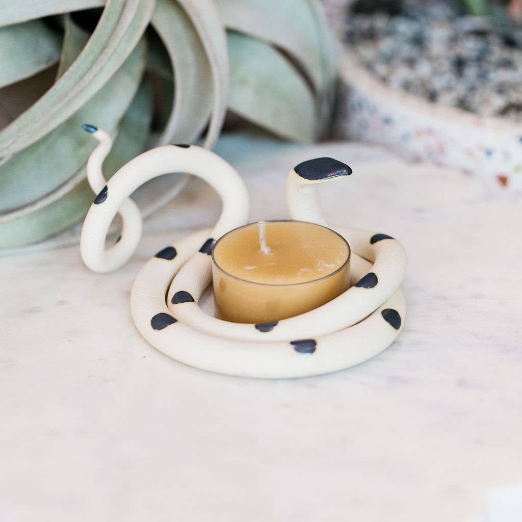 White ceramic snake tealight holder with black spots and a black head, coiled around a beeswax tealight