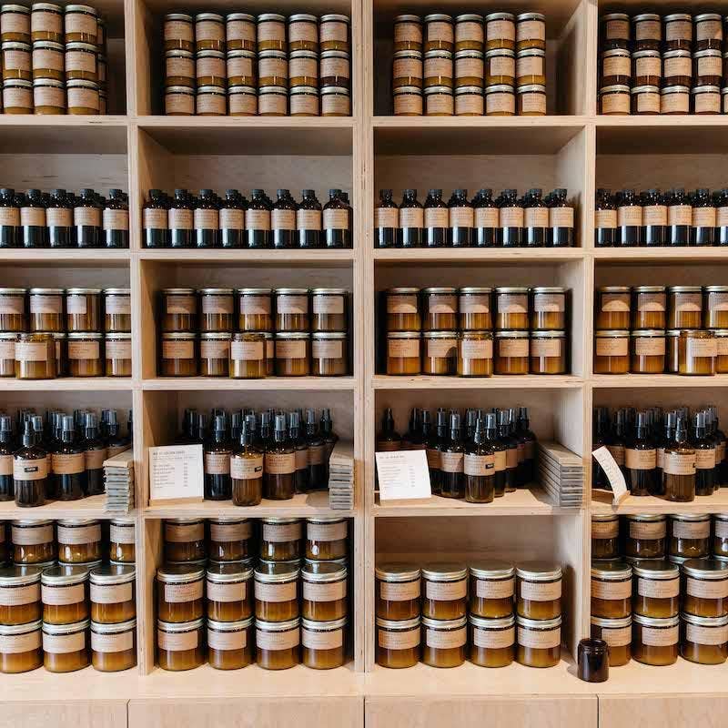 Wall of wooden shelves stocked with amber jar candles and diffuser bottles with kraft labels
