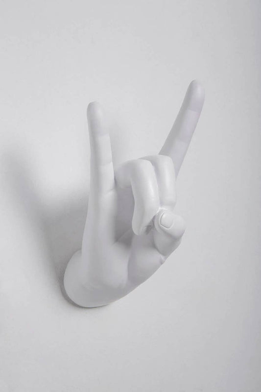 White Rock On hand wall hook making the horns gesture, shown at an angle on a white wall