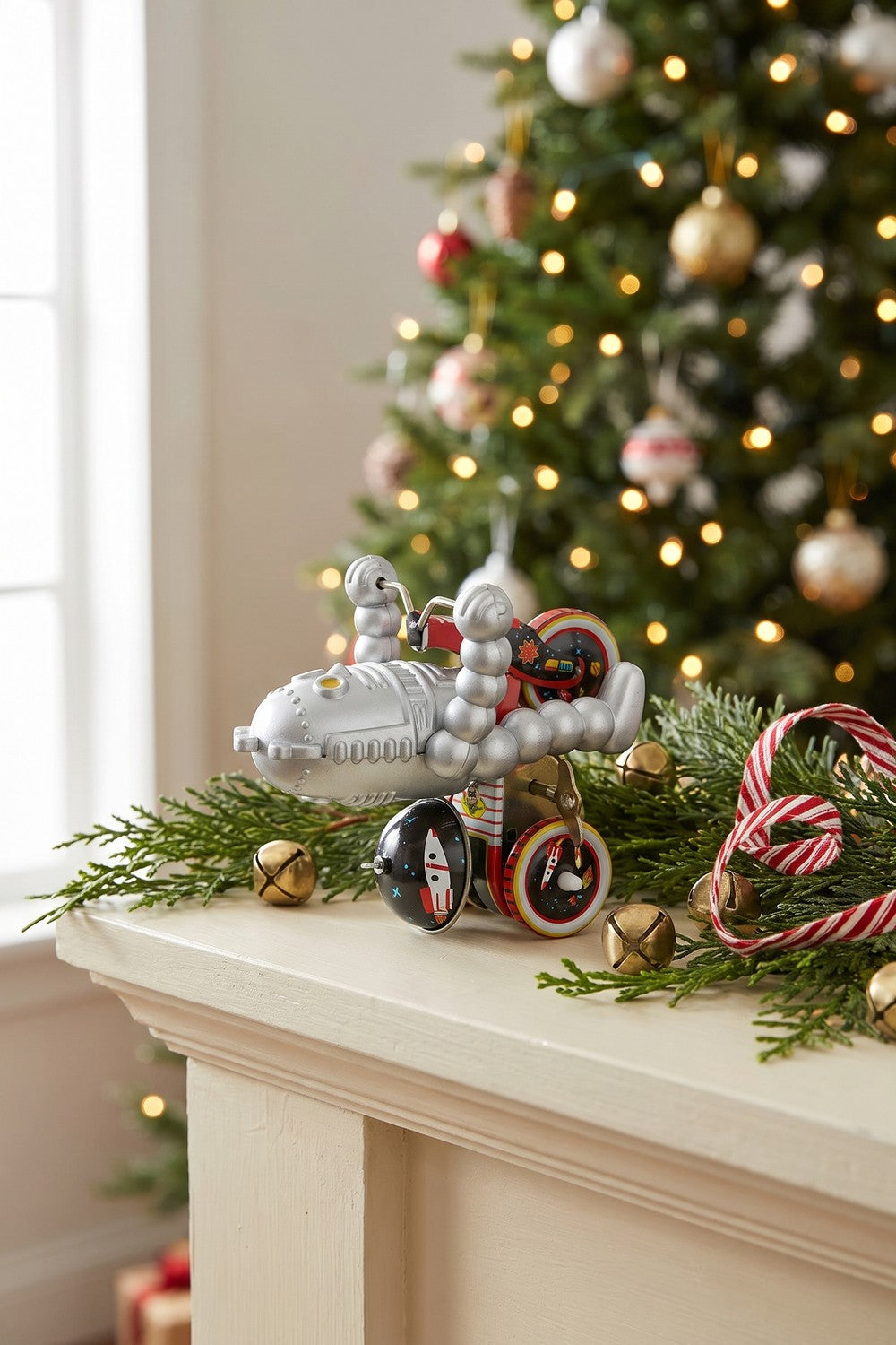 Tin robot on tricycle on a holiday mantel with evergreen garland