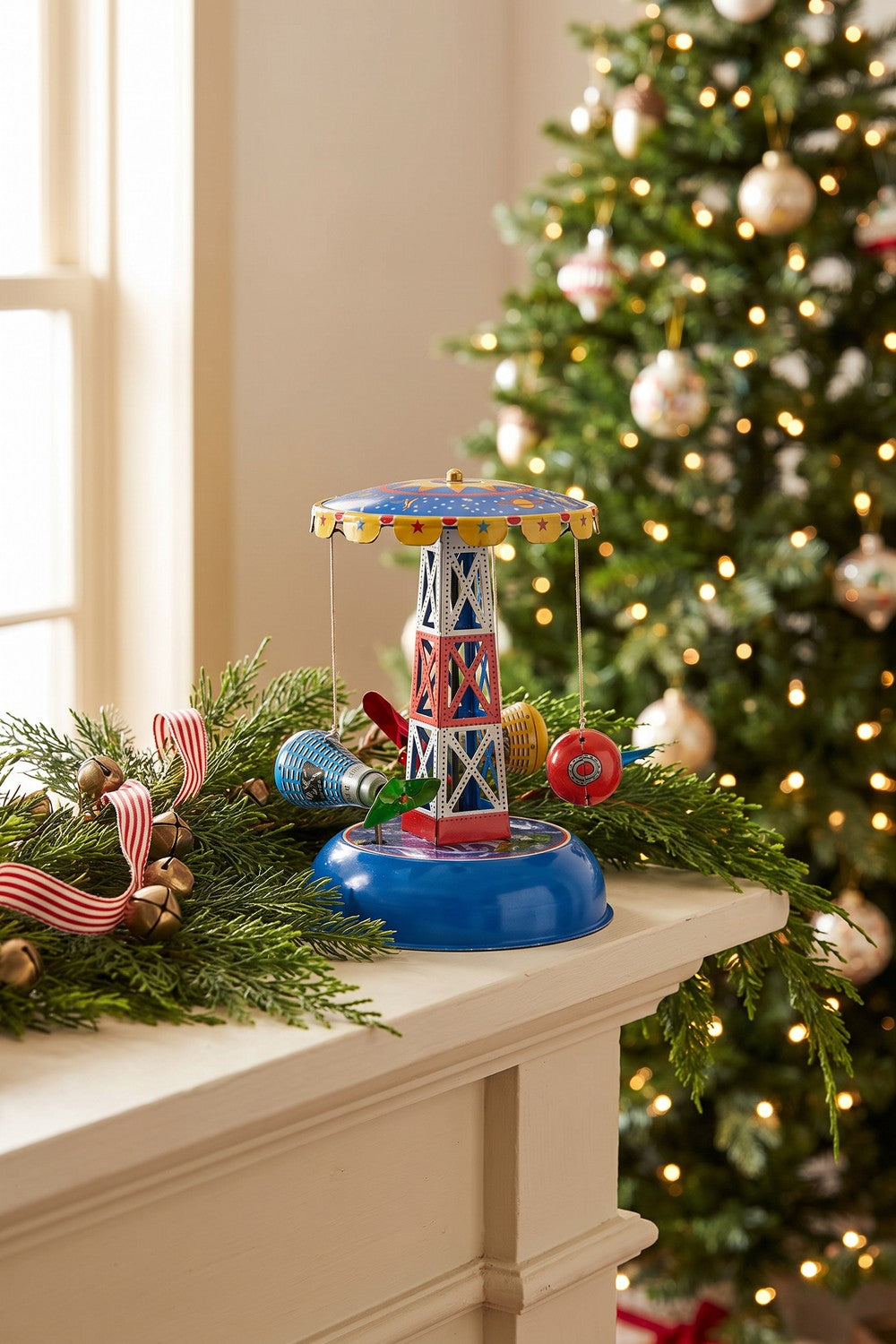 Space capsule tin carousel on a holiday mantel with evergreen garland