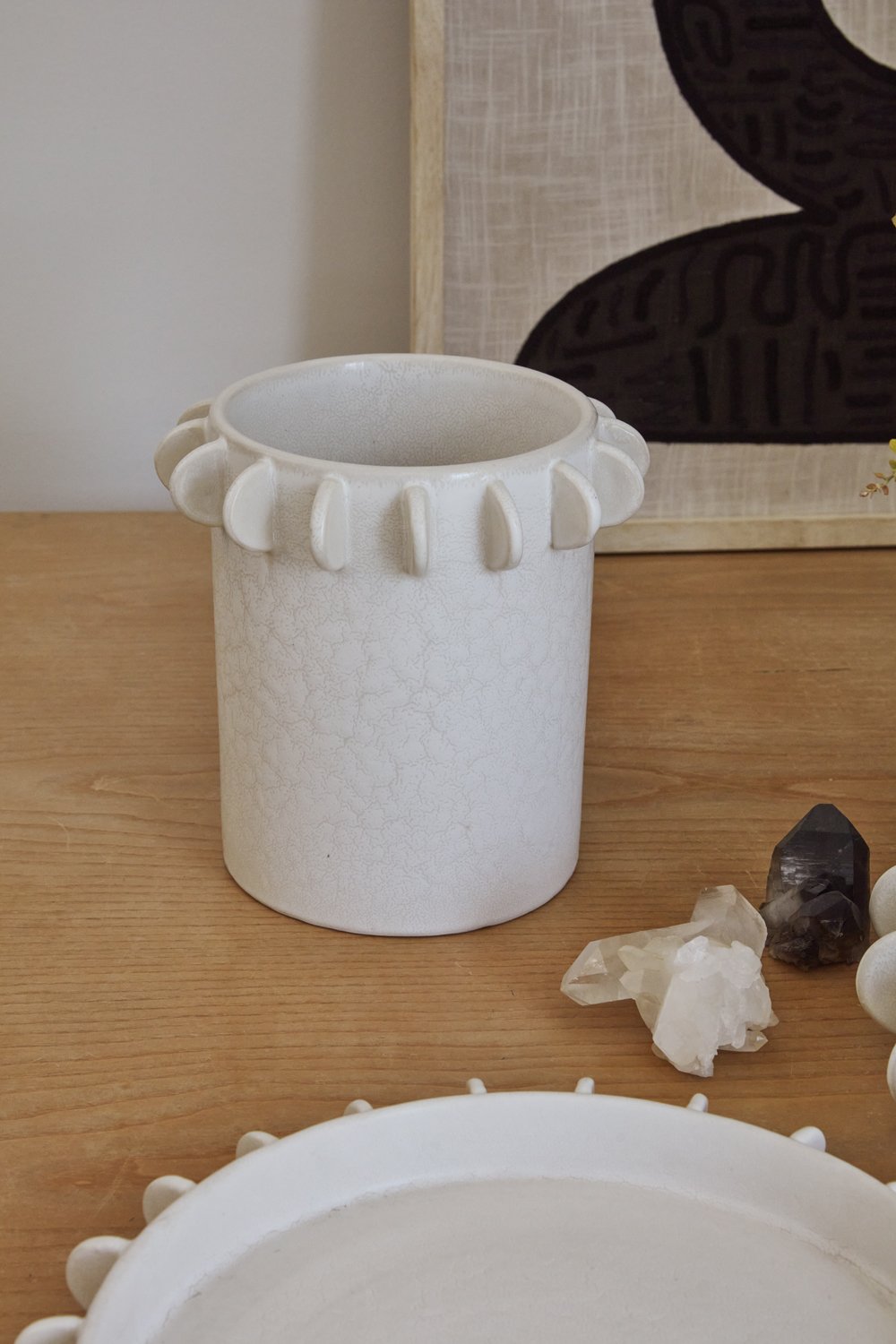 Large Reverie canister on a wood table with quartz crystals and a scalloped white tray