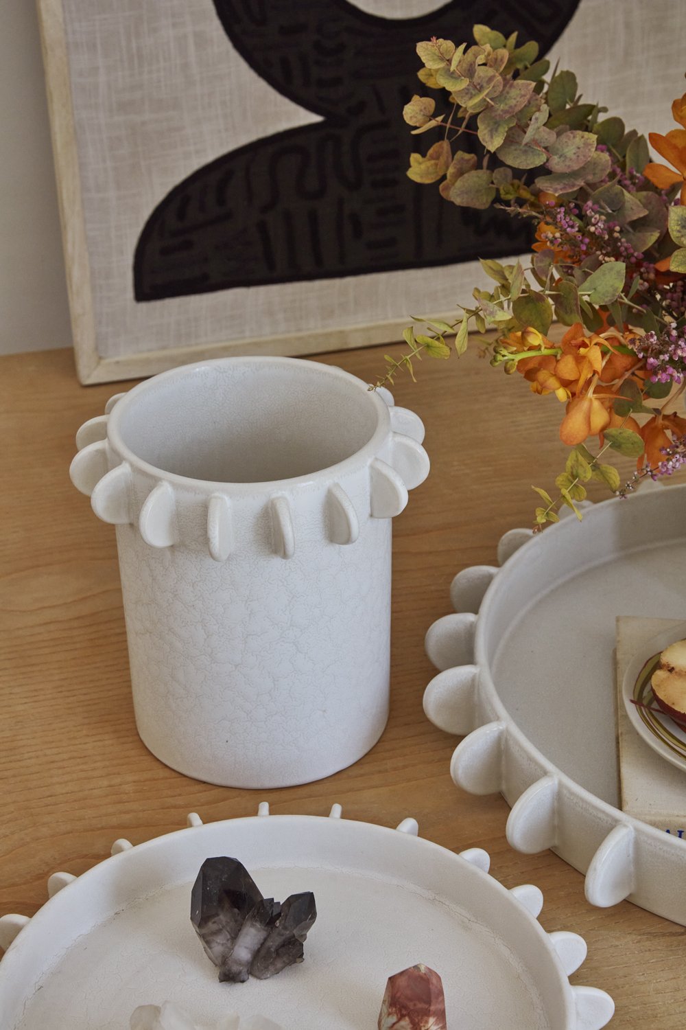 Large Reverie canister beside a dried floral arrangement and a matching scalloped tray
