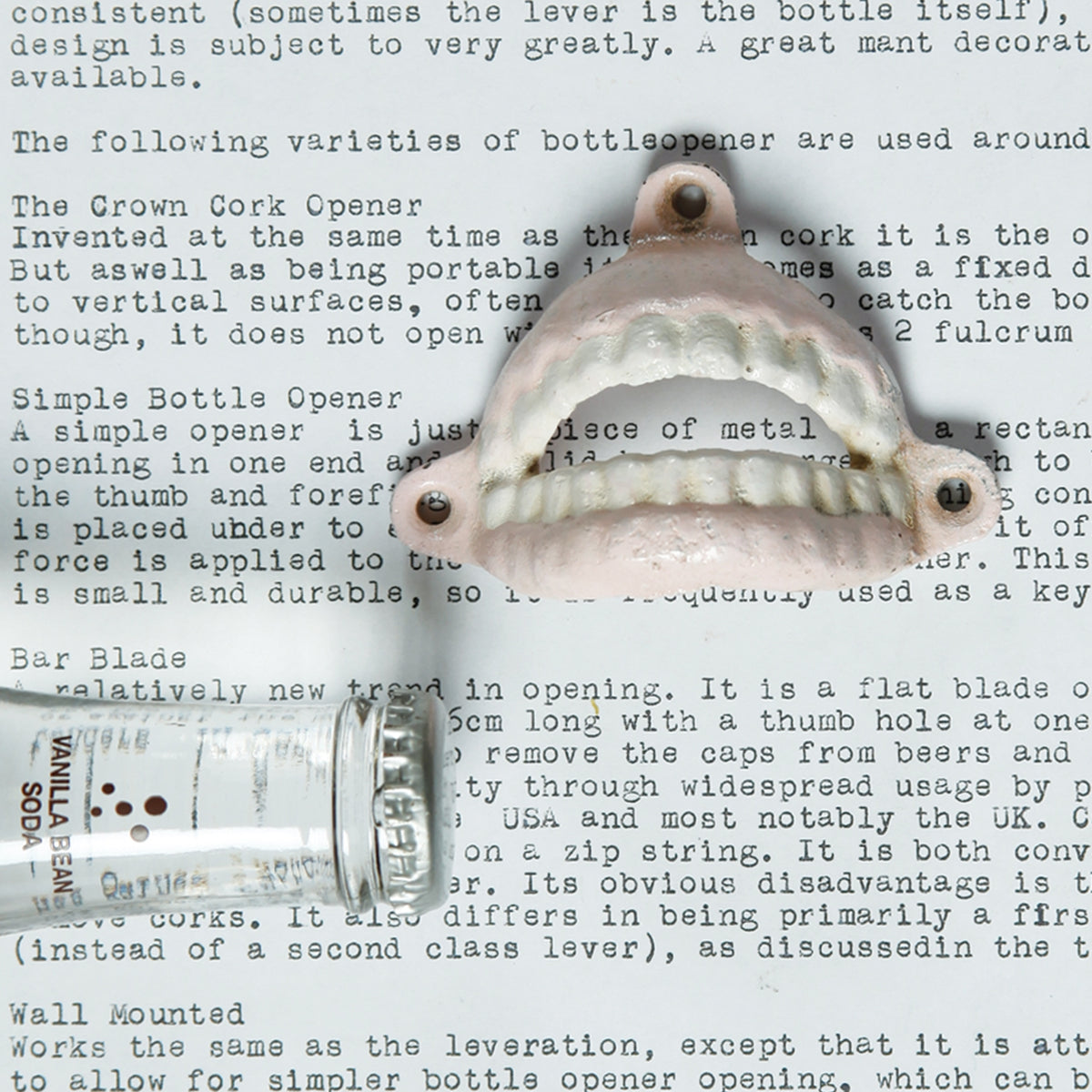 Denture bottle opener on a typed page about bottle openers next to a glass soda bottle