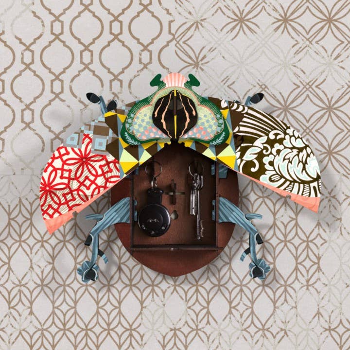 John Beetle wall cabinet with patterned wings open to reveal key hooks and keys on a patterned wall