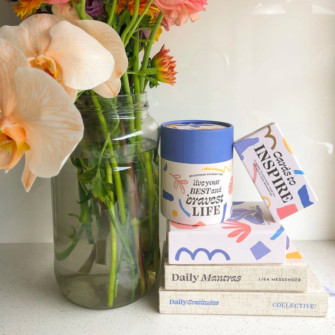 Assortment of inspirational cards and books next to a vase with flowers.