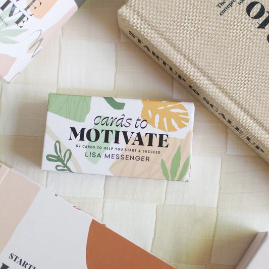 Cards to motivate box on top of quilt next to other books.