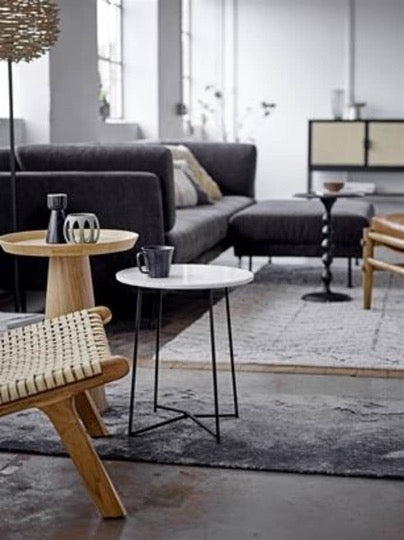 Modern living room setting with nesting tables and gray sofa and ottoman in background