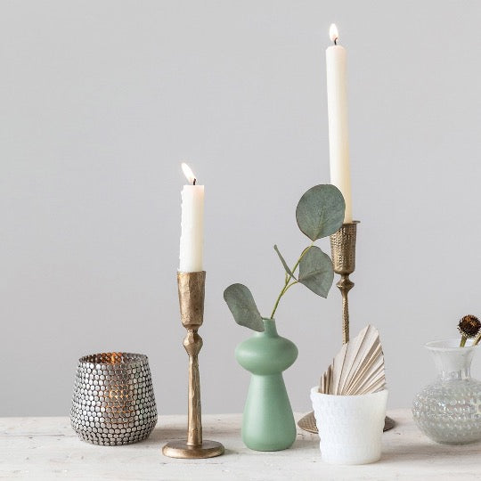 aqua bud vase with 2 brass taper holders with candles lit. 