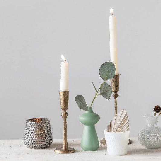 aqua bud vase with 2 brass taper holders with candles lit. 