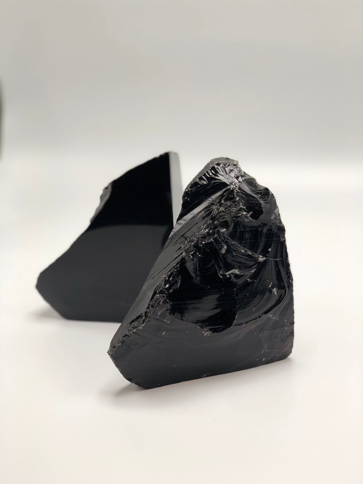 Close-up of a black obsidian bookend's rough, glassy natural edge with the second half behind it